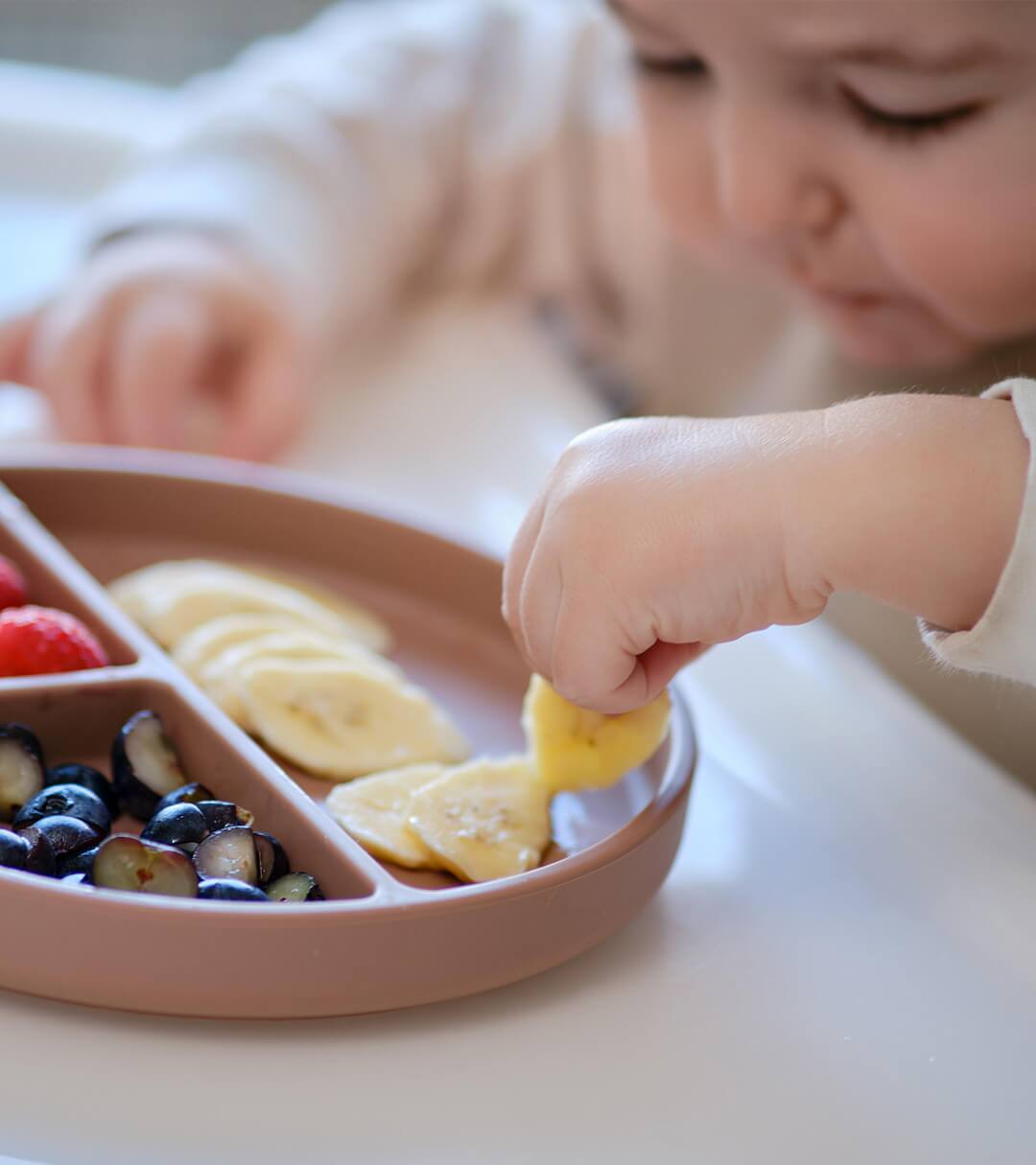 Baby eating fruits out of a silicone tray