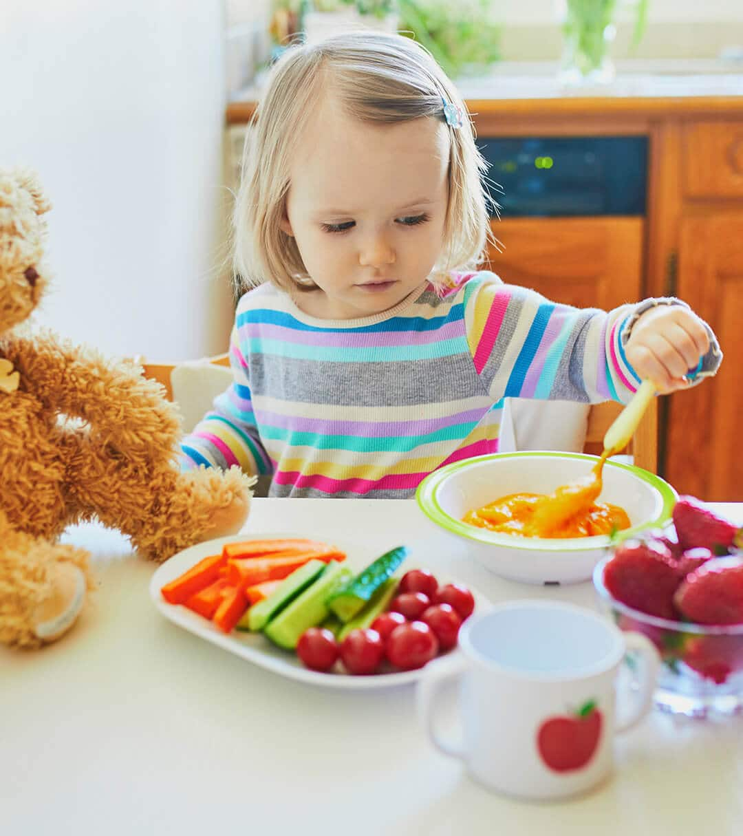 Toddler sitting on a table and eating