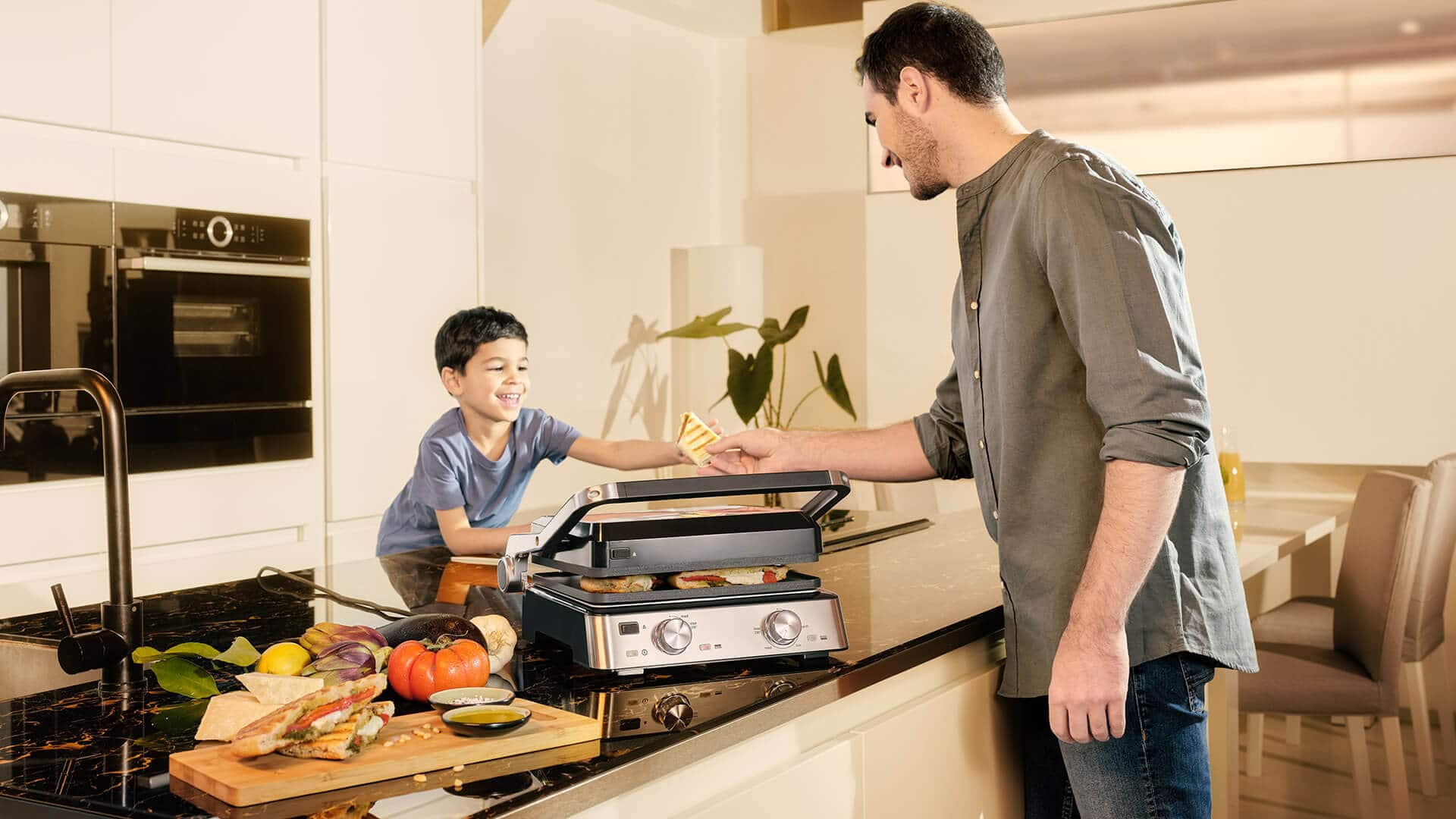 Braun MultiGrill 7 in use. Man with boy in kitchen.